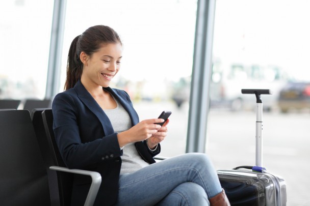 Airport business woman on smart phone at gate