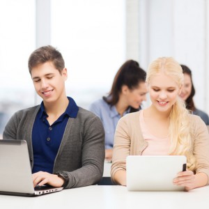 two smiling students with laptop and tablet pc