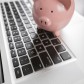 Piggy Bank Resting on Laptop Computer Keyboard.