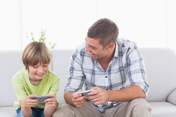 Happy father and son playing games on cell phone at home