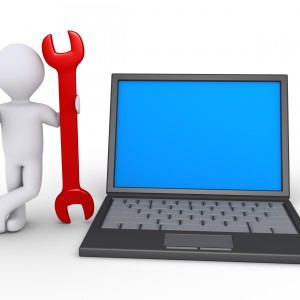 Person is holding wrench beside a computer