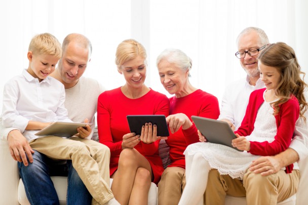 smiling family with tablet pc computers at home