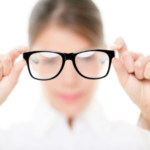 Glasses - optician showing eyewear. Closeup of glasses, with glasses and frame in focus. Woman optometrist on white background.