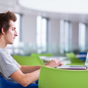 college student using his laptop computer (shalow DOF; color toned image)
